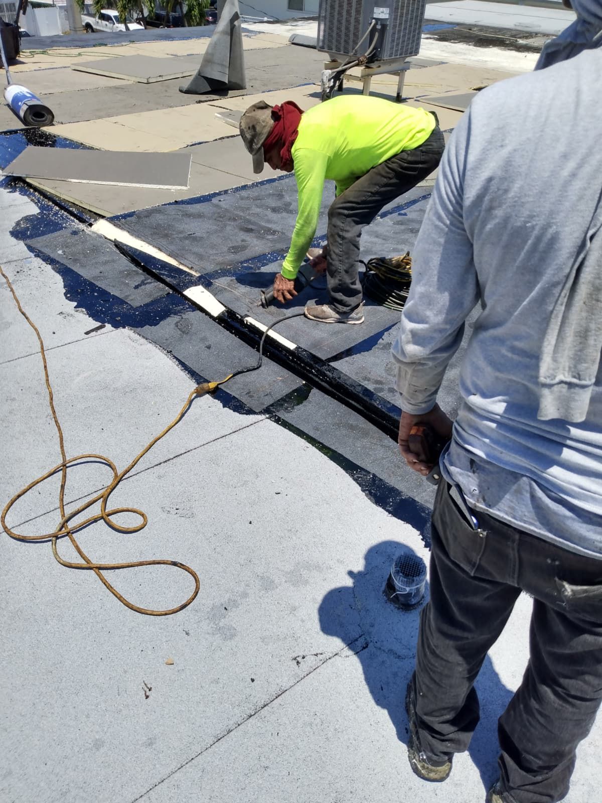 Roofing crew installing a flat-roof membrane