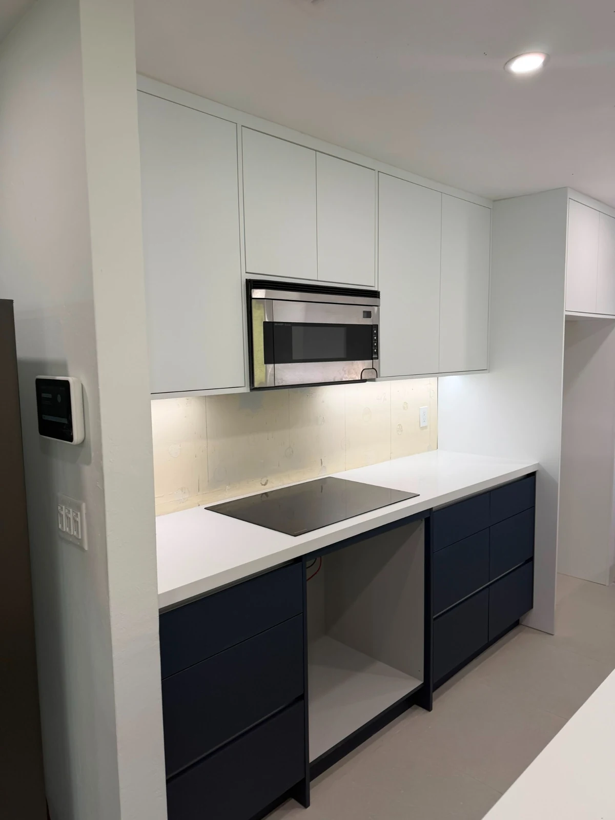 Detail of white upper cabinets and navy lower cabinets around a kitchen sink