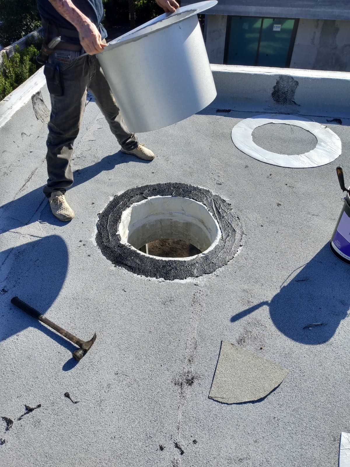 Worker preparing a circular opening on a flat roof.