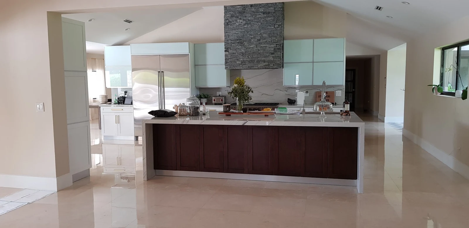 Kitchen with a dark wood island, white cabinets and a stone-clad range hood