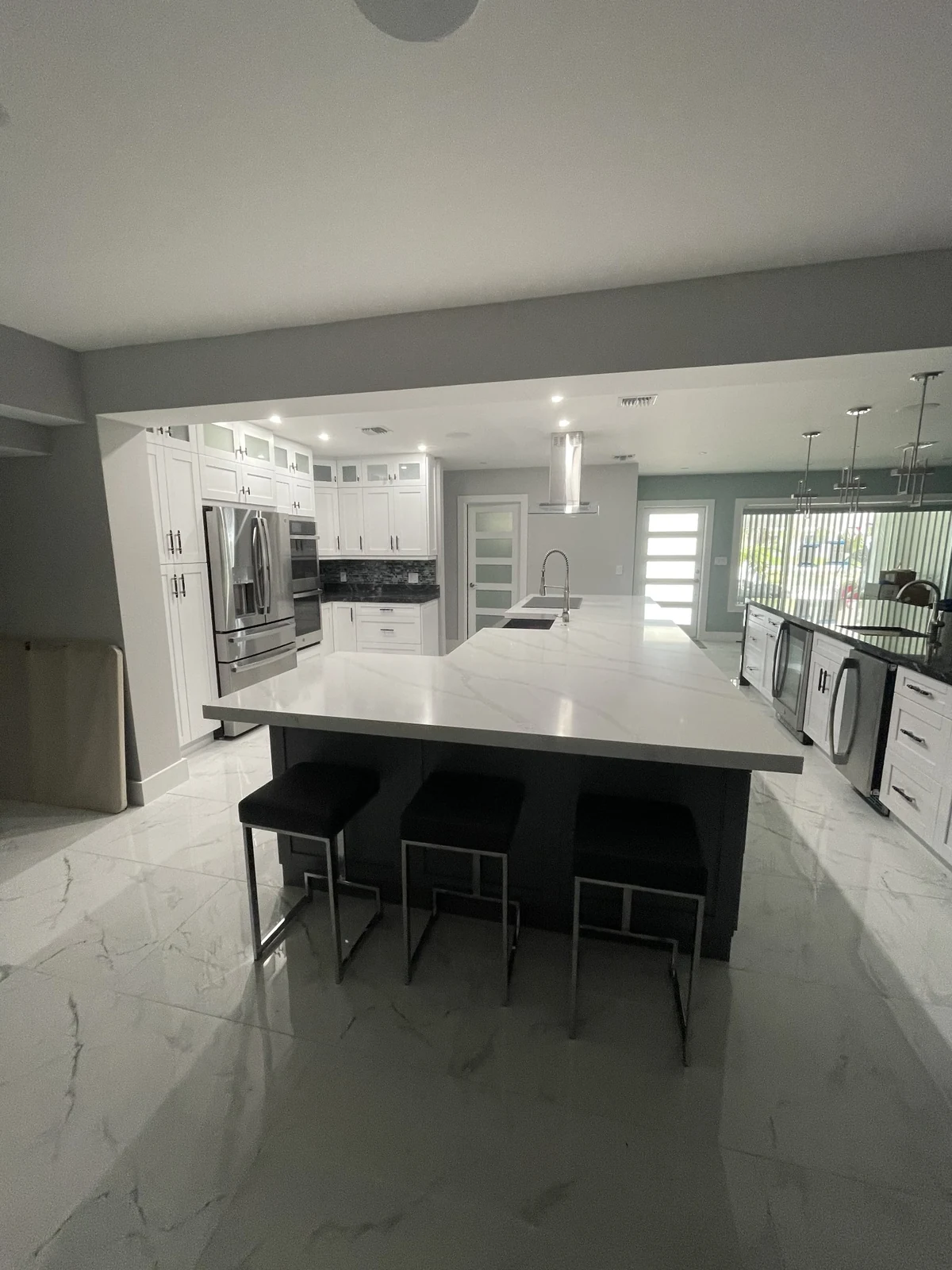 Kitchen island with dark base cabinets and seating viewed from the adjoining room