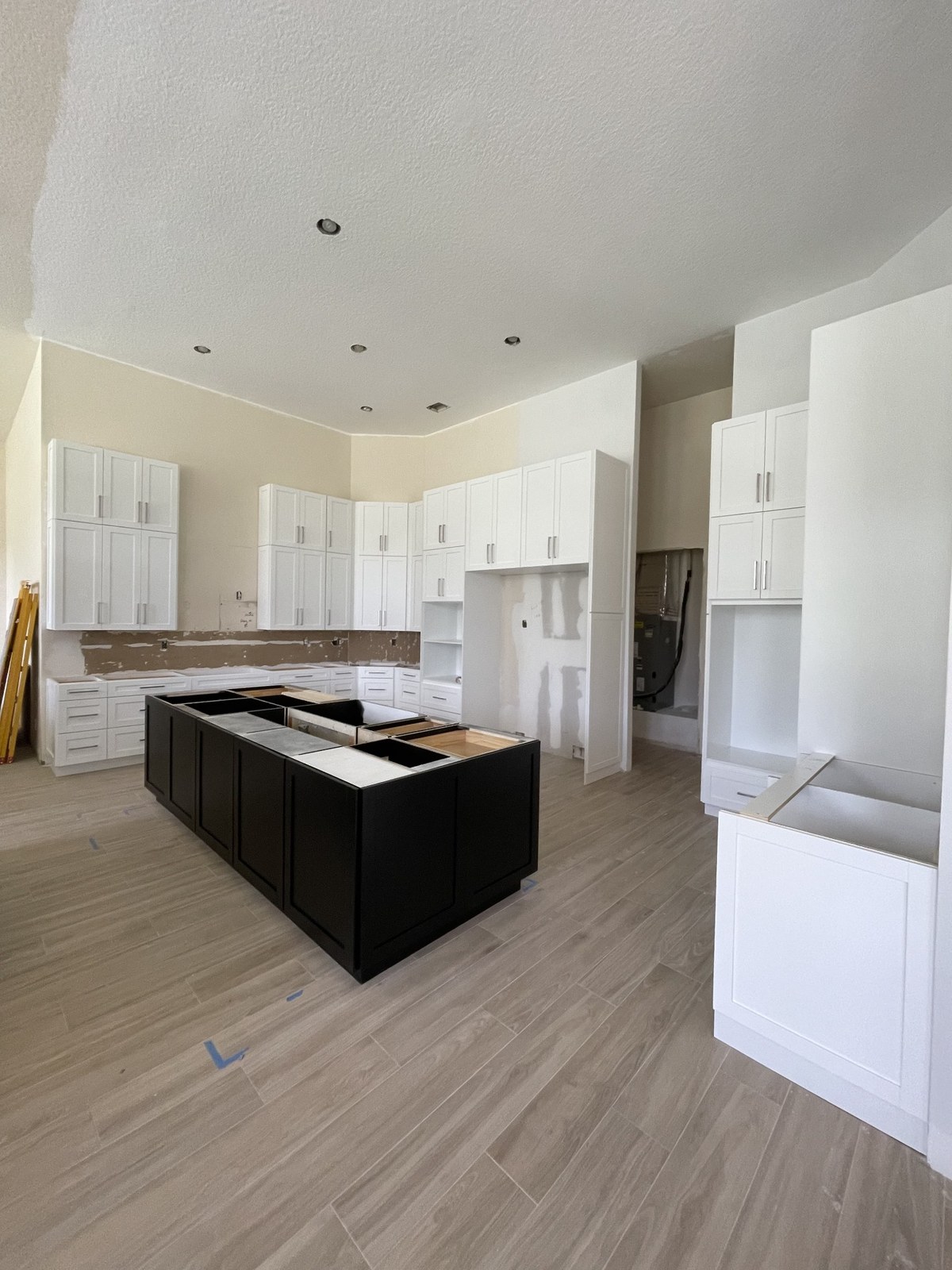 Wood-look plank flooring beneath unfinished kitchen cabinetry and an island during renovation