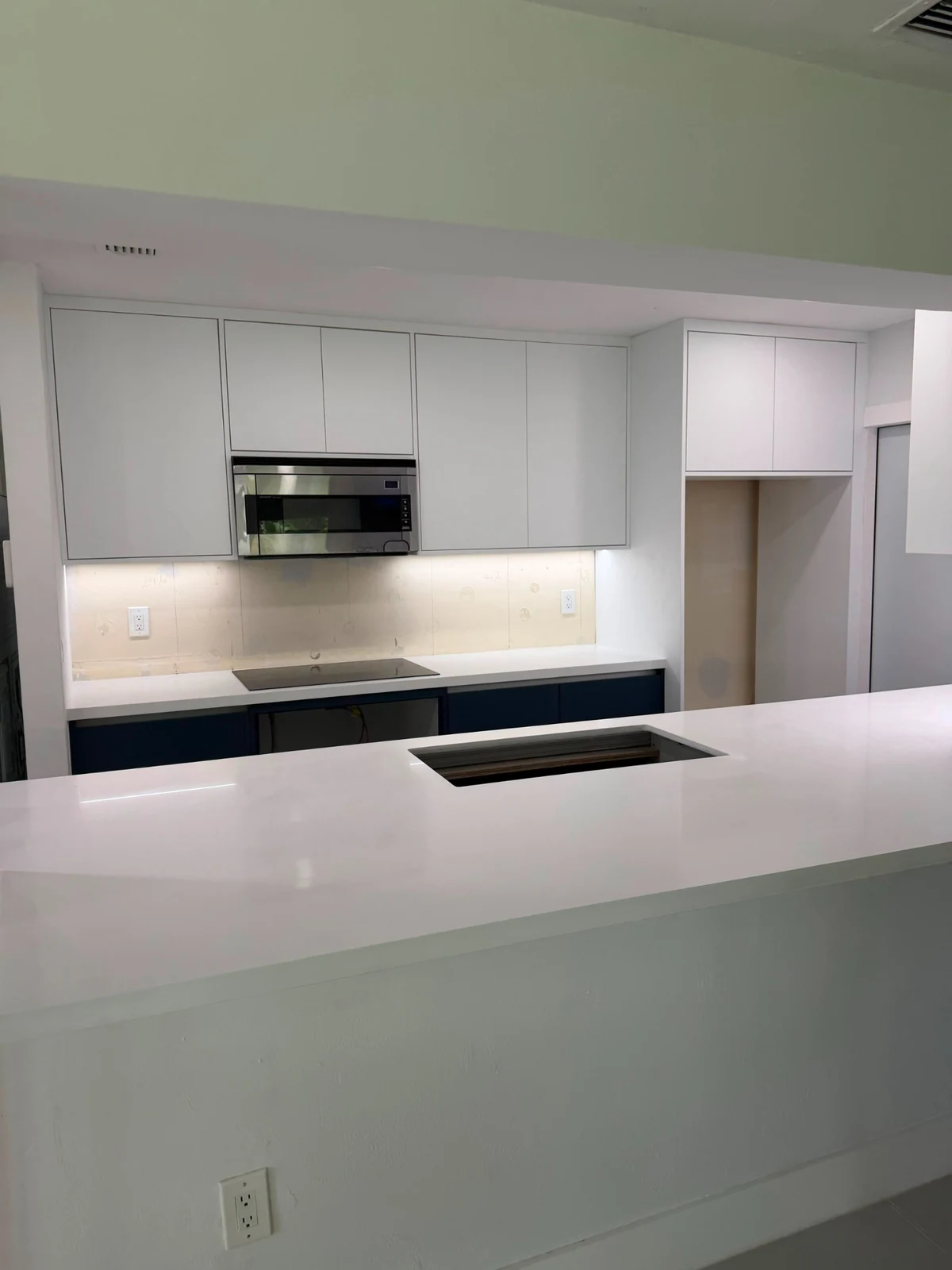 Front view of white countertops and navy kitchen base cabinets