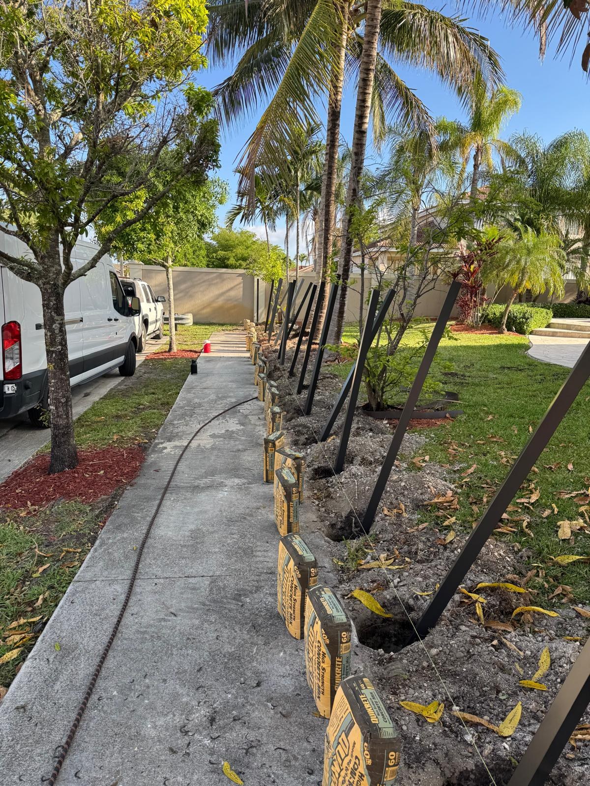Fence posts set alongside a sidewalk during installation