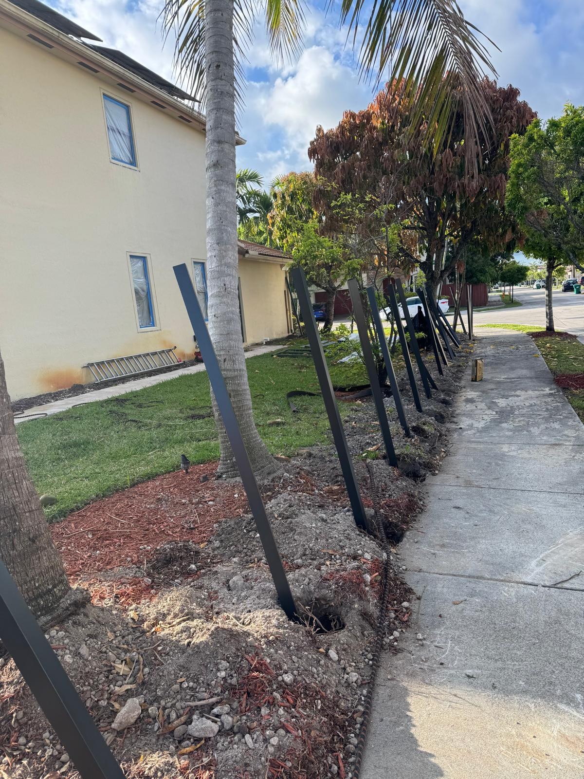 Side view of fence posts and frame beside a sidewalk